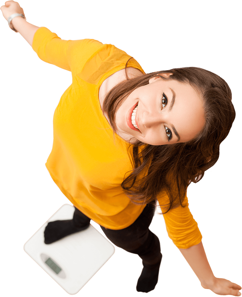 A young woman stands with one leg and outstretched arms on a bathroom scale. She looks up at the camera, smiling.